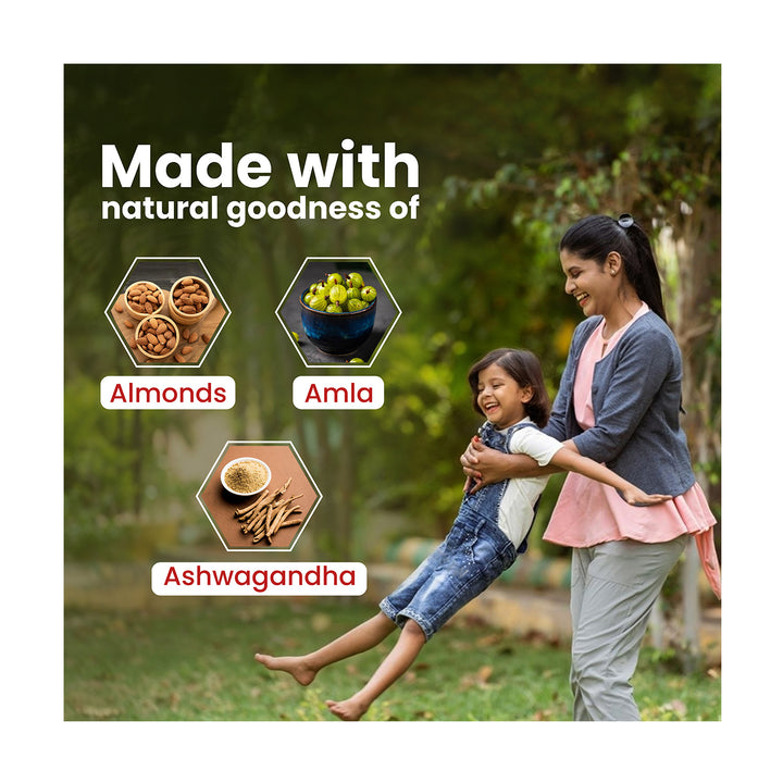 In a garden, a mother is playing with her child, surrounded by the natural goodness of almonds, amla, and ashwagandha.